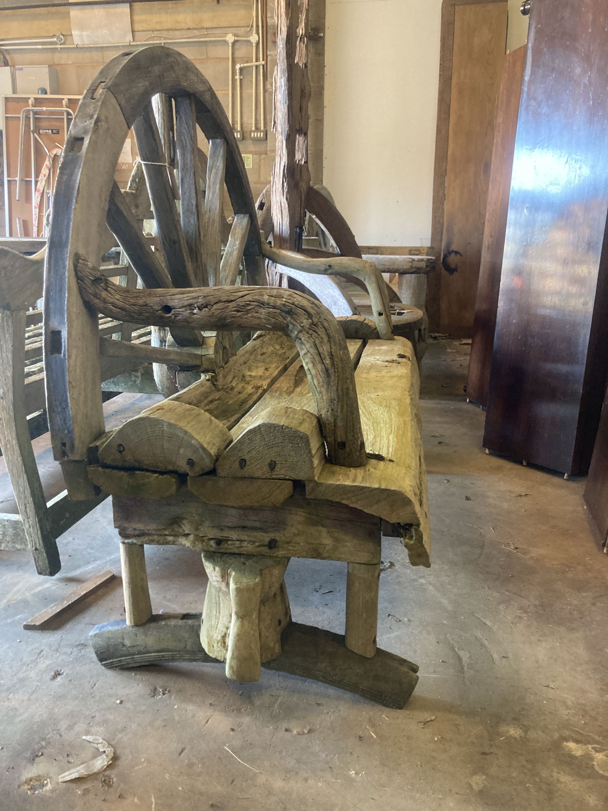 A weathered hardwood cartwheel garden bench, width 140cm depth 70cm height 116cm